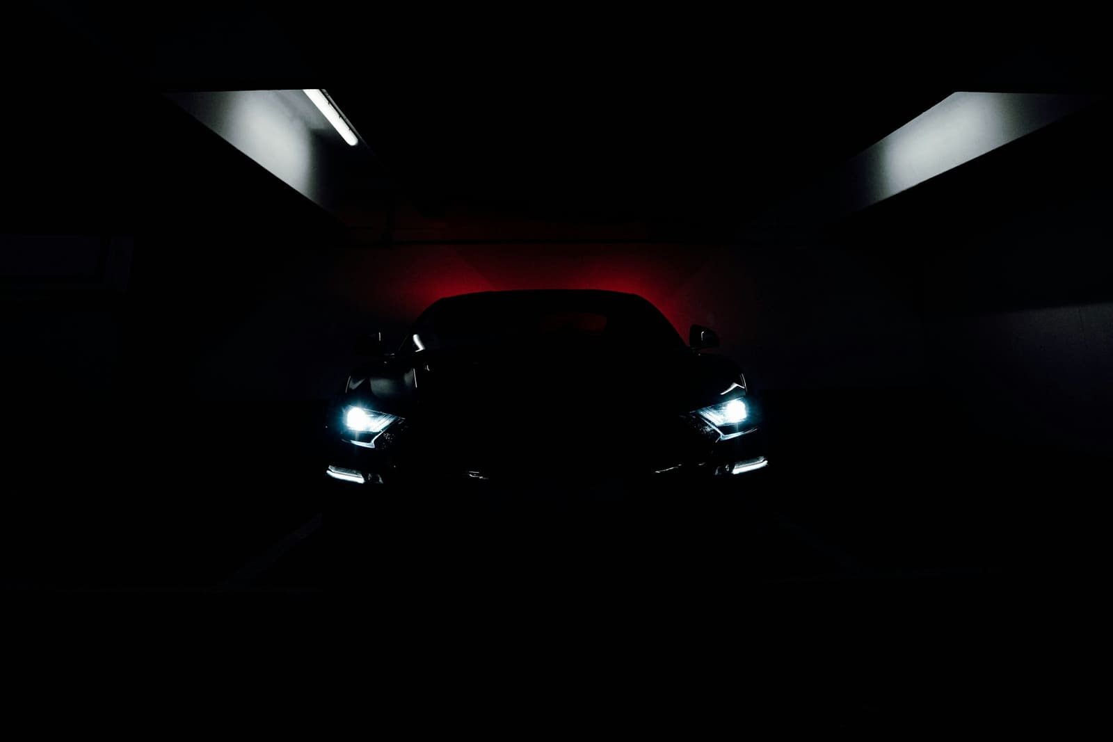 Coupé negro con faros encendidos en un garaje oscuro