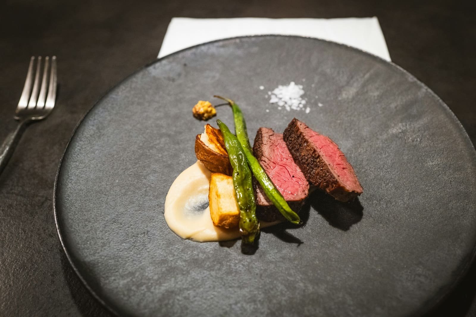 Carne a la brasa con verduras en plato oscuro