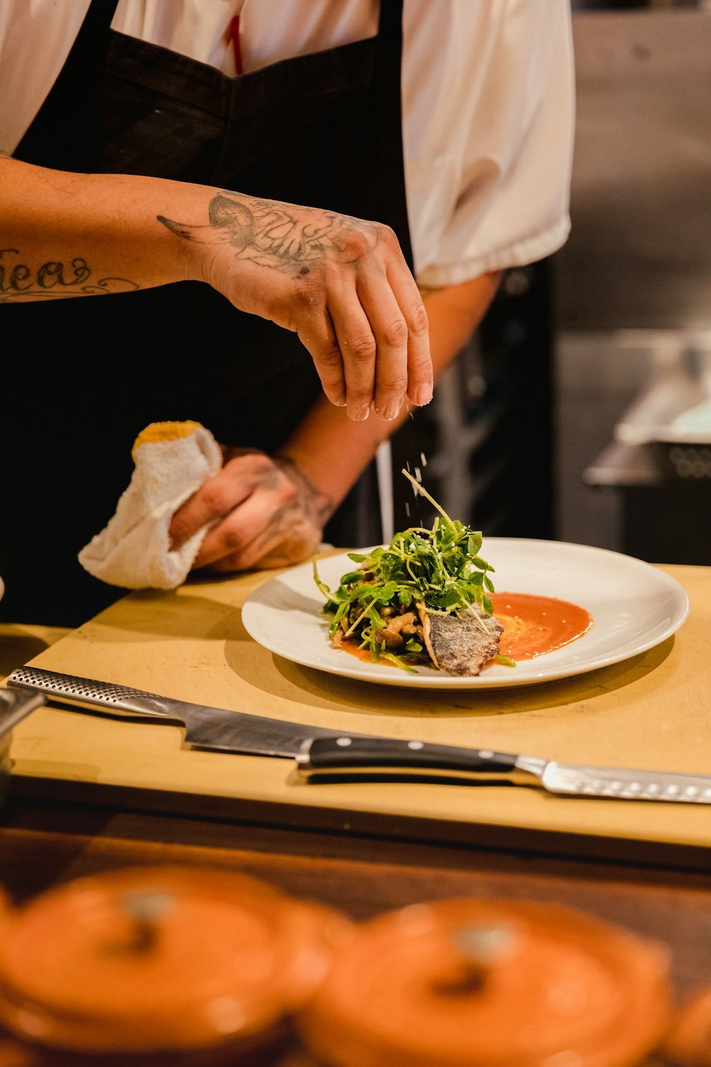 Cocinero emplatando verduras con pinzas