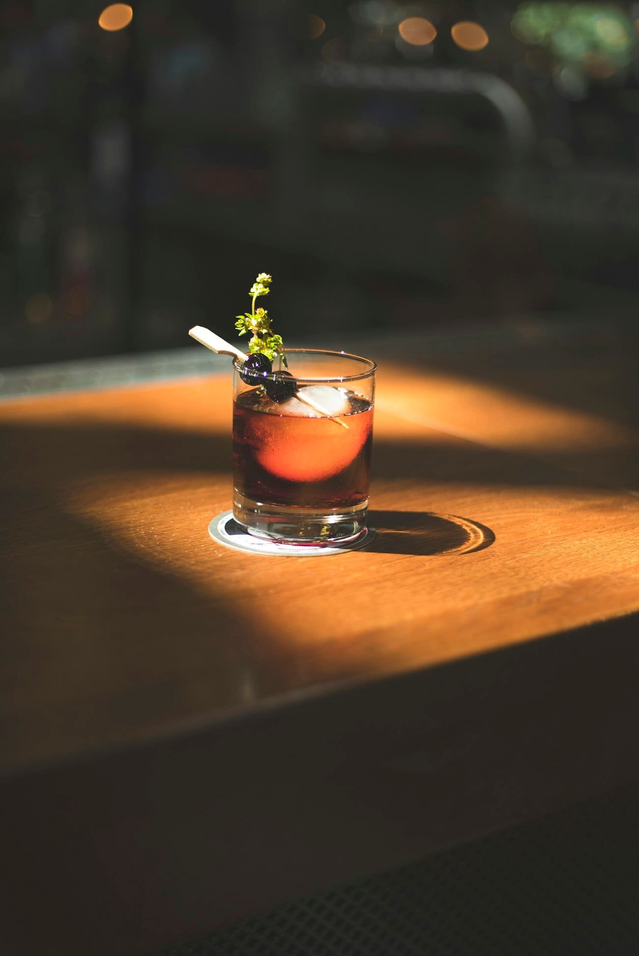 Cóctel ámbar con hierbas en vaso bajo