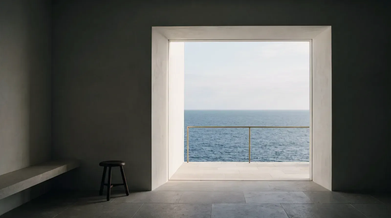 Sala en penumbra abierta a un gran ventanal con el mar al fondo