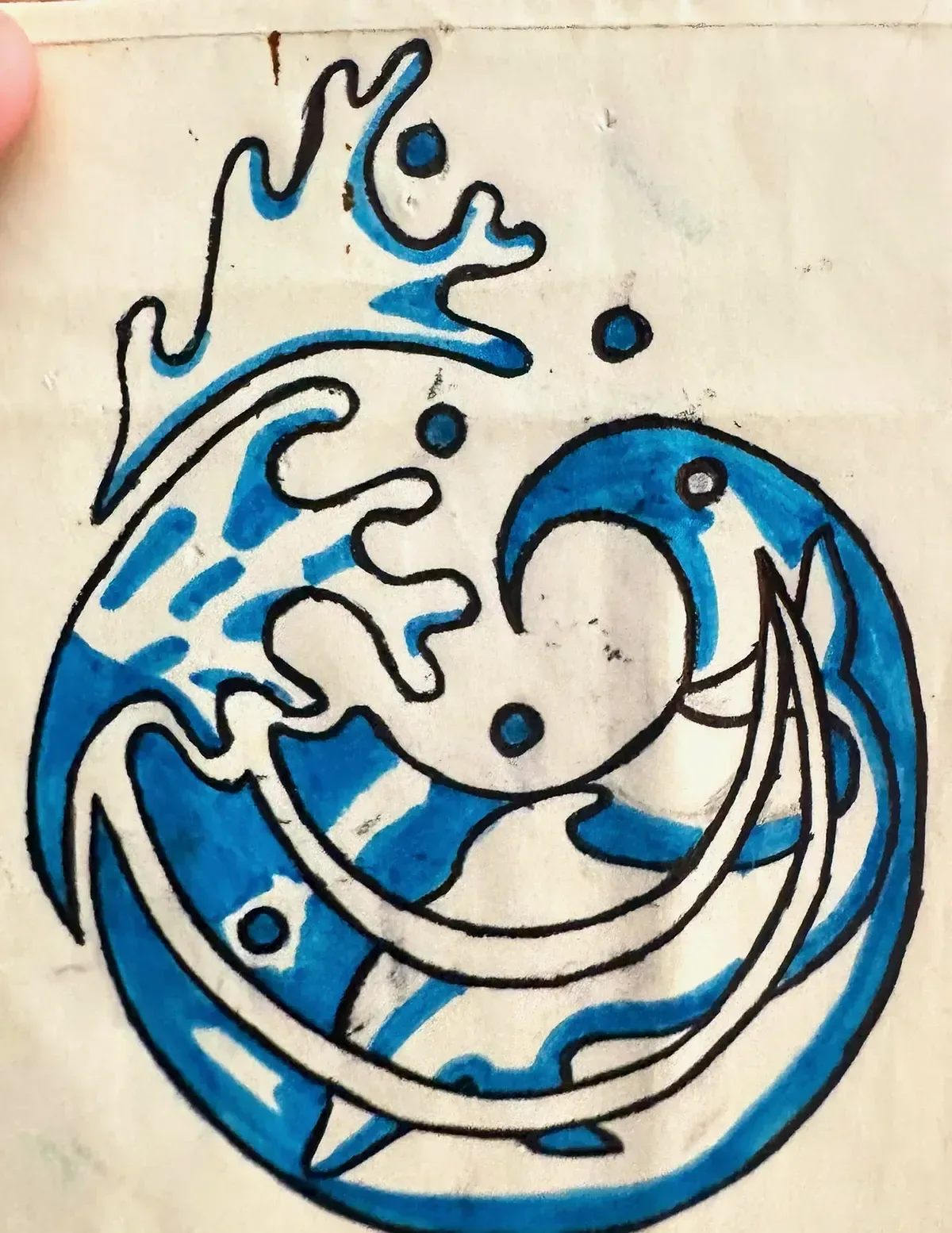 El dibujo original sobre papel: una ola que se cierra en círculo con un delfín integrado, con el contorno en negro y el relleno de rotulador azul.