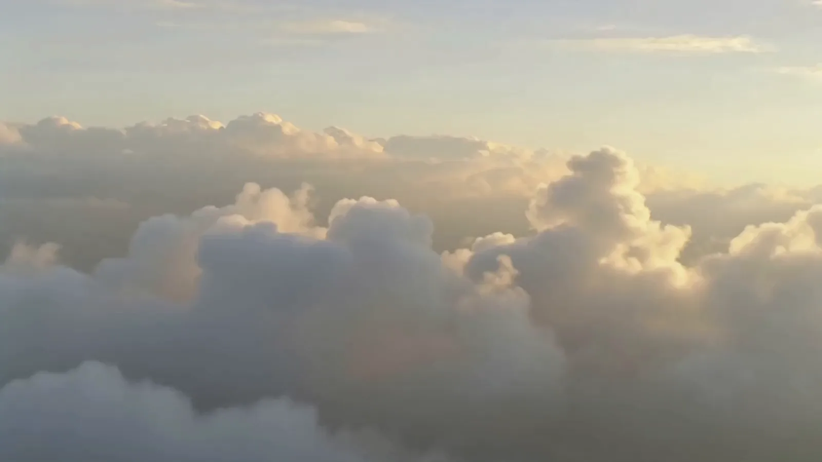 Vuelo sobre un mar de nubes a la hora dorada, con los bancos pasando por debajo.